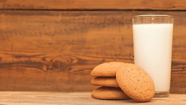 Sklenici mléka a ovesné sušenky na tmavém pozadí, detail — Stock fotografie