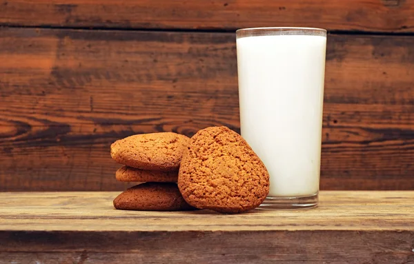 Sklenici mléka a ovesné sušenky na dřevěné pozadí — Stock fotografie