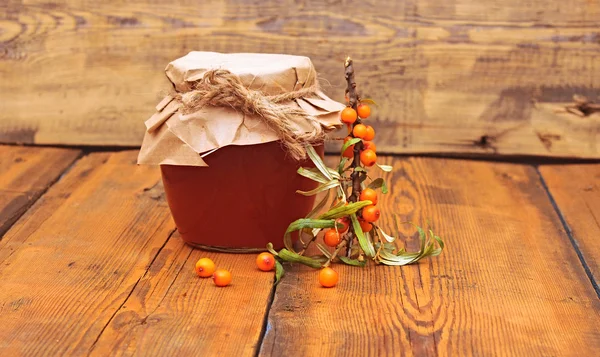 Mar buckthorn bagas suco no frasco de vidro em backgroun de madeira — Fotografia de Stock