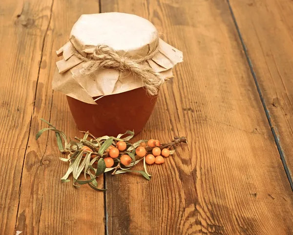 Mar buckthorn bagas suco no frasco de vidro na mesa de madeira — Fotografia de Stock