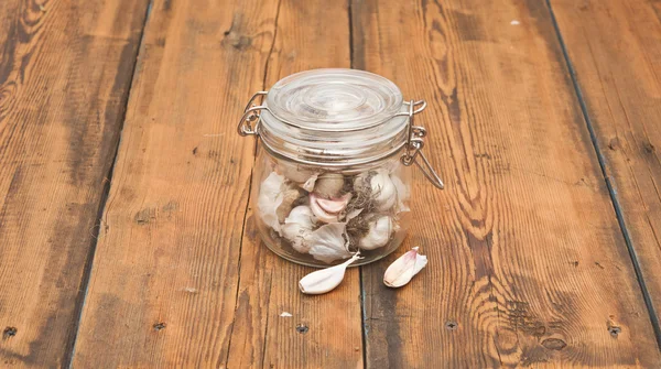 Свіжий часник у скляній банці на старому дерев'яному столі — стокове фото