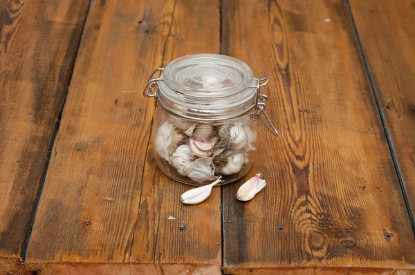 Färsk vitlök i glasburk på gammalt träbord — Stockfoto
