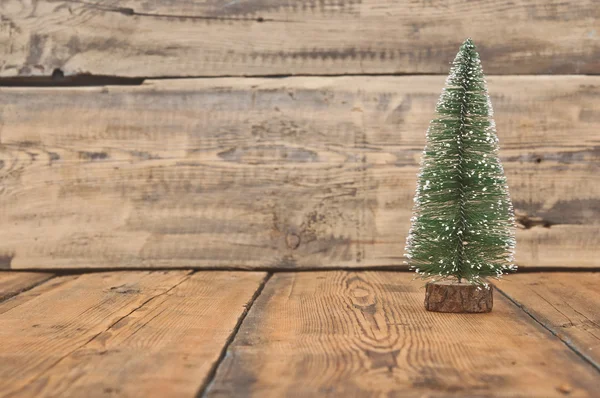 Pequeño árbol de navidad de juguete en una vieja mesa de madera — Foto de Stock