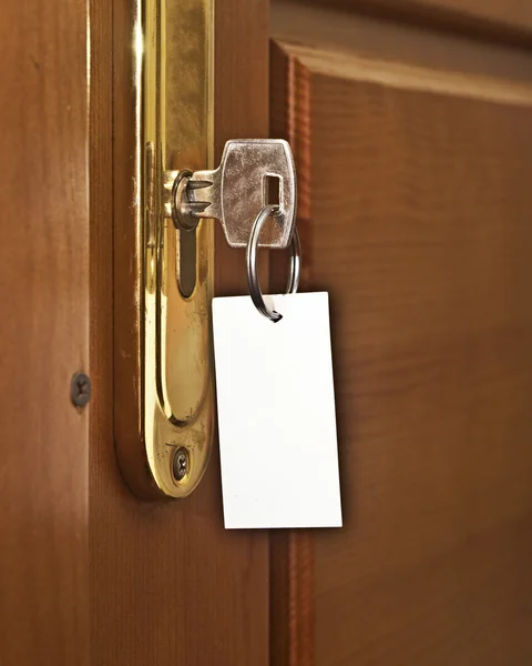 Schlüssel im Schlüsselloch mit leerem Etikett — Stockfoto