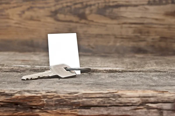 Clé avec une étiquette vierge sur une vieille table en bois — Photo