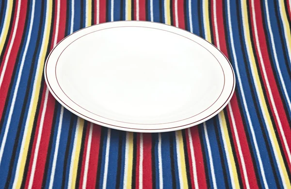 Empty plate on colorful tablecloth — Stock Photo, Image