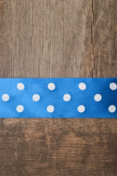 Houten achtergrond met blauwe polka-stip lint — Stockfoto