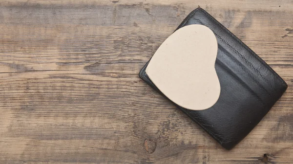 Czarny skórzany portfel z papieru serca na tle drewniane — Zdjęcie stockowe