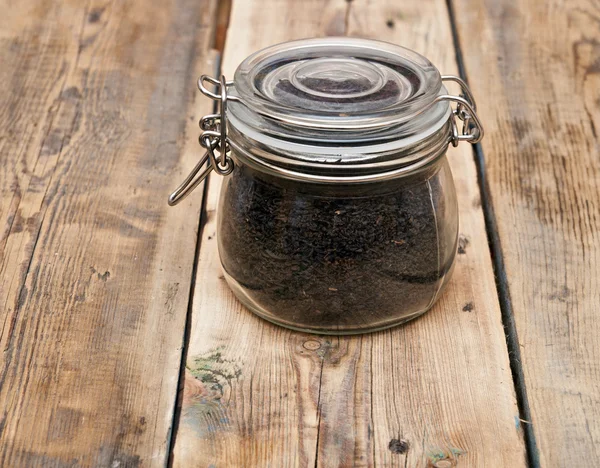 Zwarte thee in glazen pot op oude houten tafel — Stockfoto