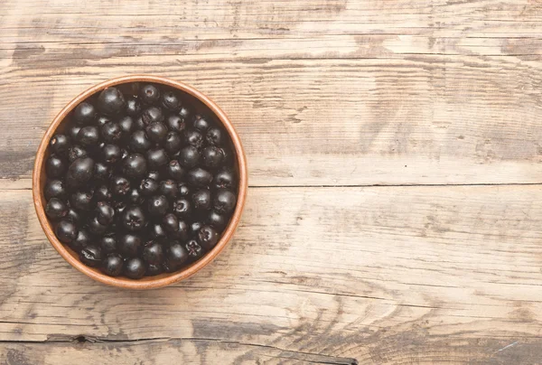 Μαύρο chokeberry σε καφέ μπολ στο ξύλινο τραπέζι — Φωτογραφία Αρχείου