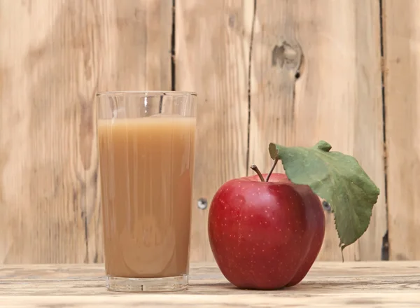 Apfel mit Apfelsaft auf einem hölzernen Hintergrund — Stockfoto