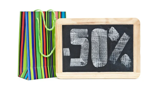 Vijftig procent geschreven op blackboard met kleurrijke boodschappentas — Stockfoto