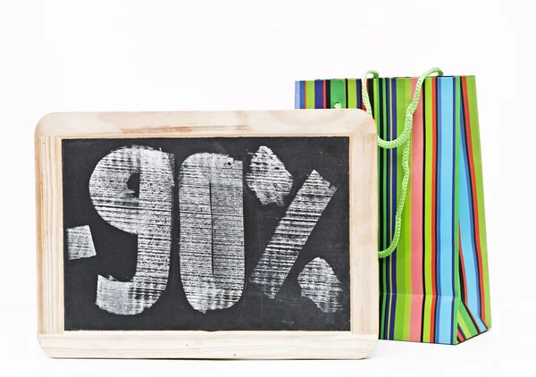 Ninety percent discount written on blackboard with colorful bag — Stock Photo, Image