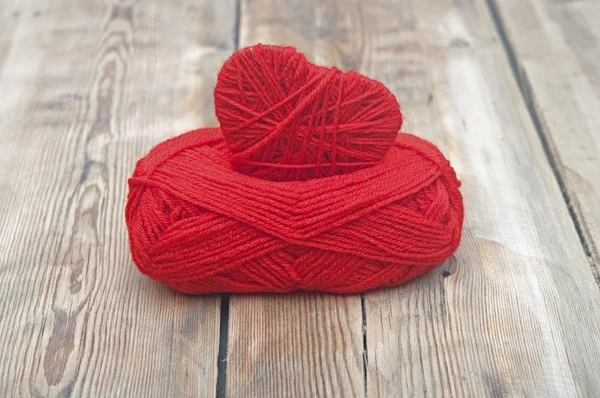 Knitted heart and red of yarn on wood background — Stock Photo, Image