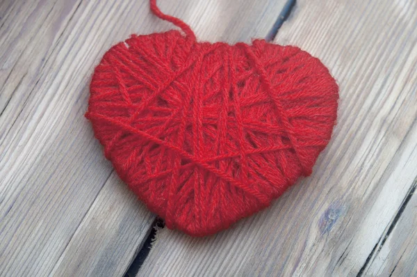 Corazón de hilo de lana roja sobre fondo de madera — Foto de Stock