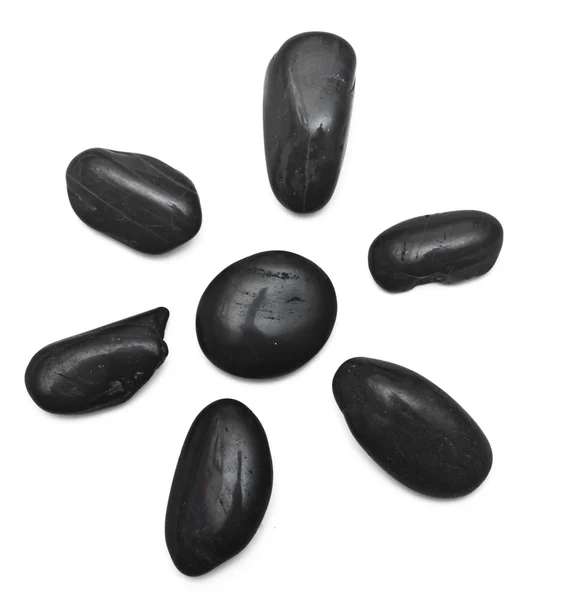 Algunas piedras negras formando una flor sobre un fondo blanco — Foto de Stock