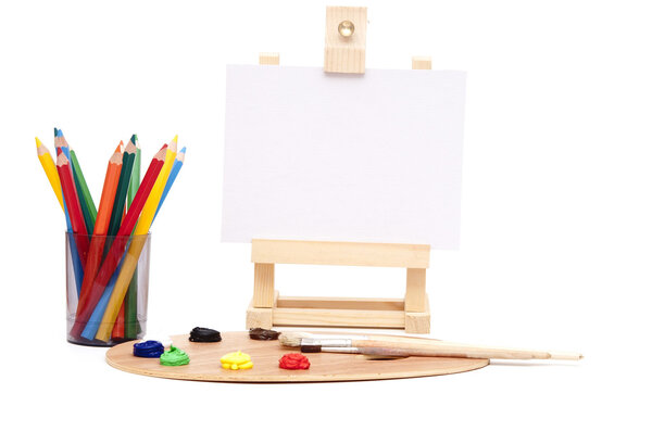 Деревянный мольберт с чистой бумагой и цветовой палитрой художника
