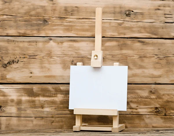 Chevalet en bois avec papier propre sur une vieille table en bois — Photo