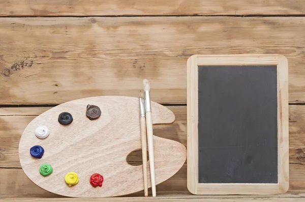 Paleta de arte de madera con pintura y pinceles sobre fondo de madera — Foto de Stock