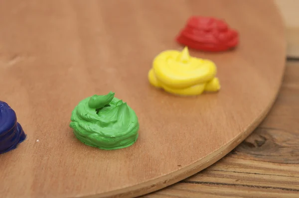 Pintura al óleo sobre una paleta sentada sobre un fondo de madera. Enfoque en gr — Foto de Stock