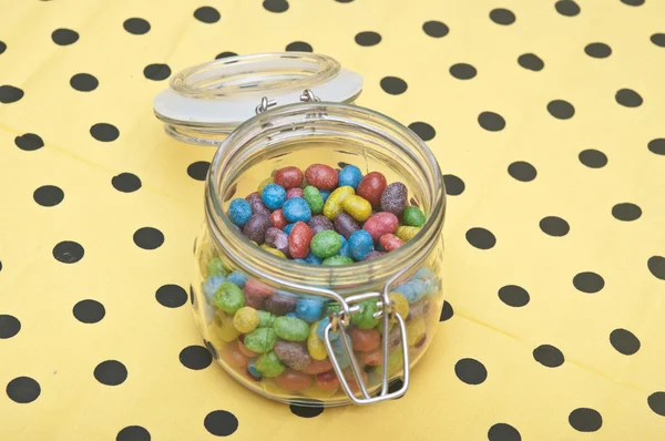 Colorful candies in glass jar on polka dot napkin — Stock Photo, Image