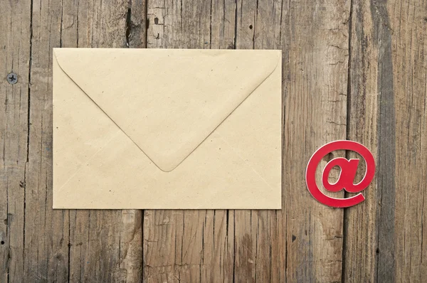 Símbolo de e-mail e envelope marrom em branco no fundo de madeira velho — Fotografia de Stock