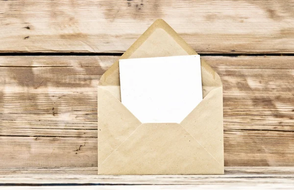 Порожня листівка та конверт на старому дерев'яному фоні — стокове фото