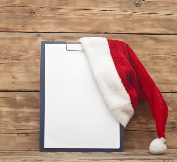 Kerstman hoed op Klembord met blanco papier blad voor uw tekst — Stockfoto