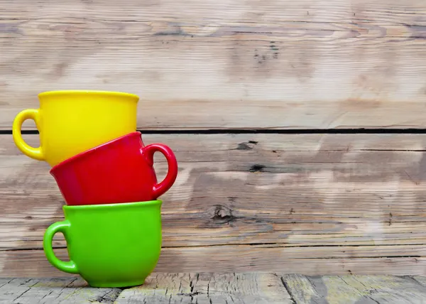 Colorful cups on the wooden background — Stock Photo, Image