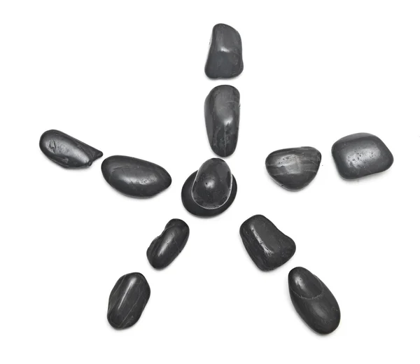 Algumas pedras pretas formando uma flor sobre um fundo branco — Fotografia de Stock