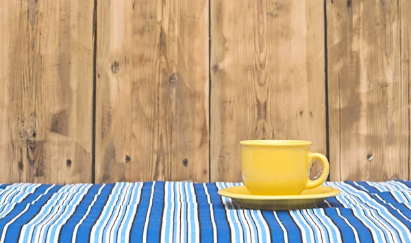 Sarı kahve fincanı ve tabağı olarak renkli bir masa örtüsü — Stok fotoğraf