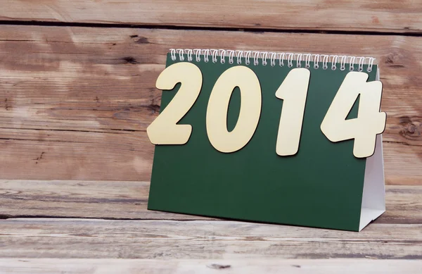 Bureaukalender met gouden nummers 2014 op oude houten tafel — Stockfoto