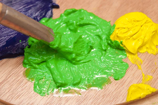 Closeup of green and yellow watercolor paints being mixed with a — Stock Photo, Image