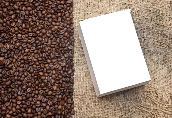 Grãos de café na antiga serapilheira e caixa em branco para o seu texto — Fotografia de Stock