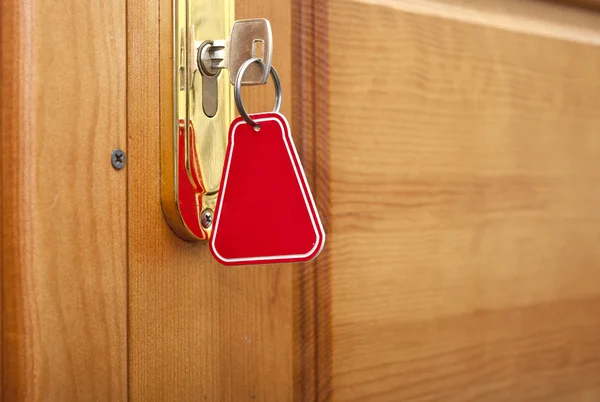 Key in keyhole with blank label — Stock Photo, Image