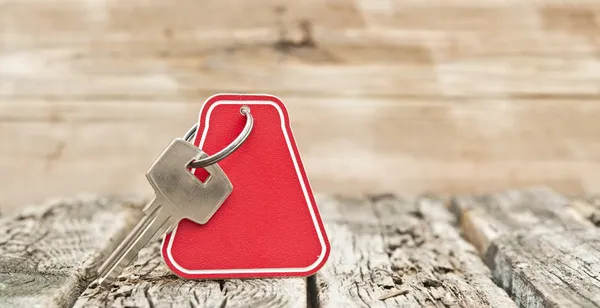 Schlüssel mit leerem Etikett auf einer alten Holzplanke — Stockfoto