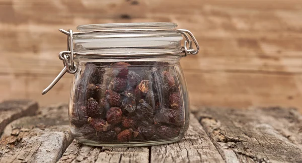 Hagebutte im Glas auf einem Holztisch. — Stockfoto