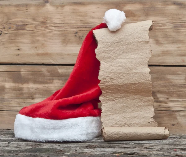 Kerstman hoed en oud papier scroll op houten tafel — Stockfoto