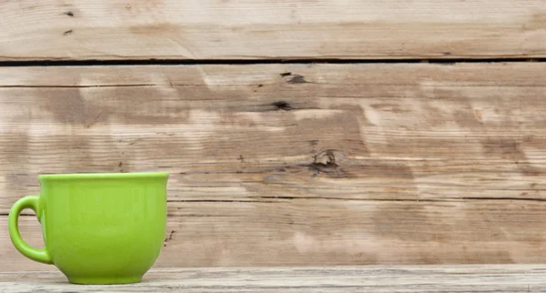 Grüne Tasse auf Holztisch über Holzhintergrund — Stockfoto