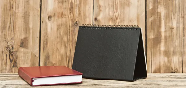 Calendário de mesa com livro de notas de couro vermelho na mesa de madeira — Fotografia de Stock