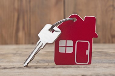 Symbol of the house with silver key on wooden background clipart