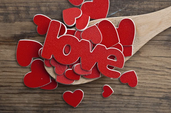 Ξύλινο κουτάλι και την λέξη αγάπη πάνω πολλές κόκκινες καρδιές — Φωτογραφία Αρχείου
