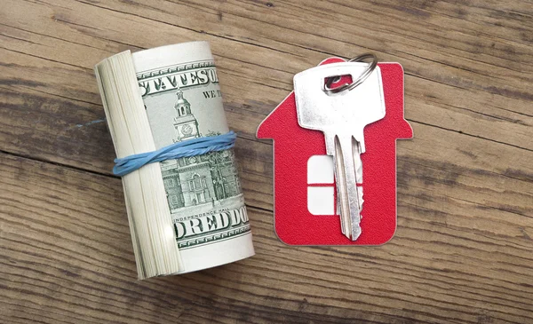 Hausschlüssel über den Hundert-Dollar-Scheinen gegen Holzrücken — Stockfoto