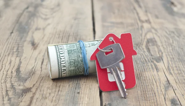 Hausschlüssel über den Hundert-Dollar-Scheinen gegen Holzrücken — Stockfoto