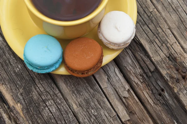 Bunte Makronen mit einer Tasse Kaffee auf altem Holzgrund — Stockfoto