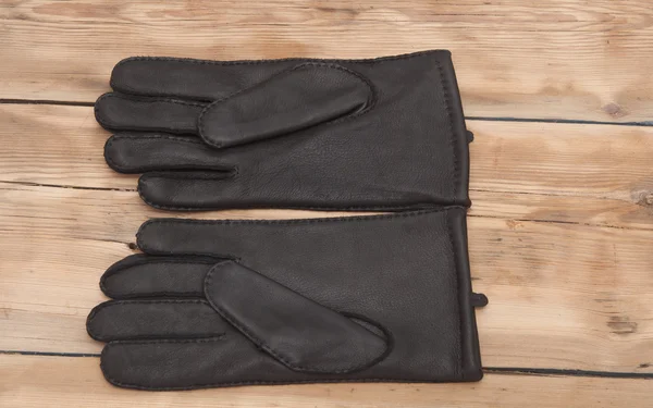 Пару мужских черных кожаных перчаток на деревянном столешнице — стоковое фото