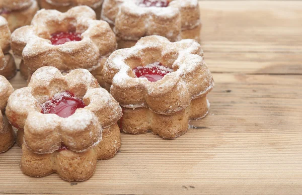 Květy tvaru cookies přikryjeme prášek cukru na dřevěný stůl — Stock fotografie