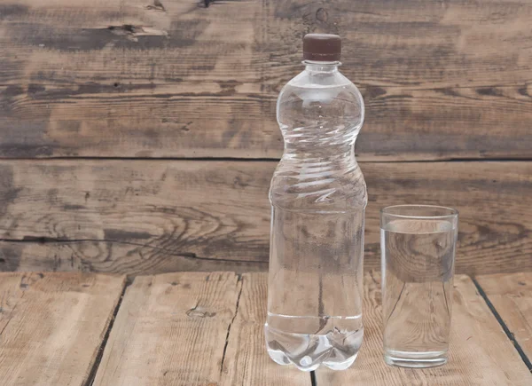 Water bottle with glass on wooden table — Stock Photo, Image