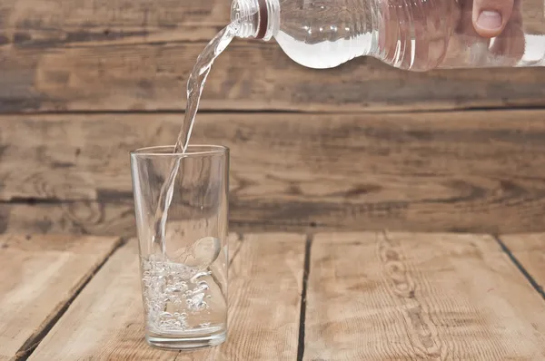 Water pour on to glass on wood table — Stock Photo, Image