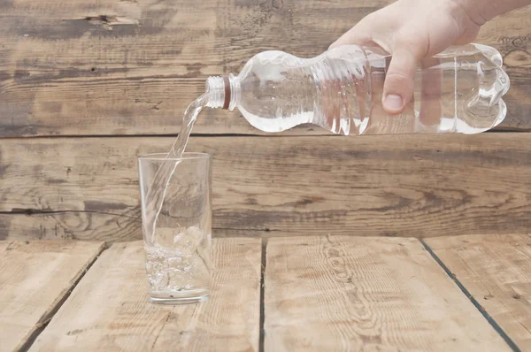 Water pour on to glass on wood table — Stock Photo, Image